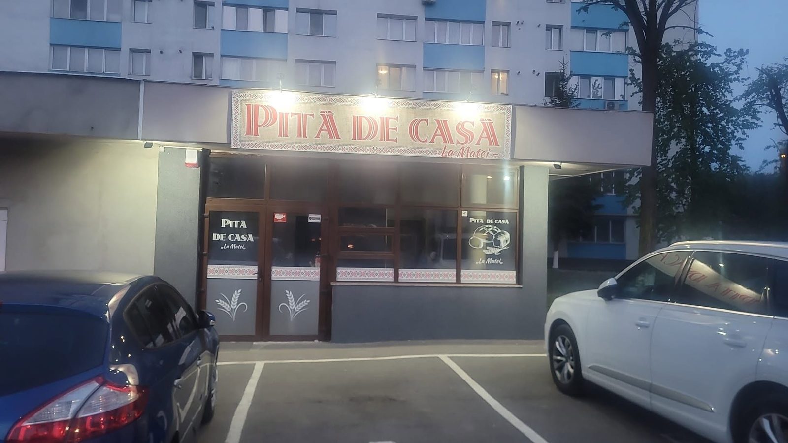 Fațada brutăriei Pită de casă La Matei, seara, cu firma luminată