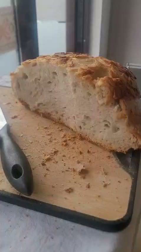 Pită tăiată, cu miezul cu ochiuri mari, pe tocător de lemn